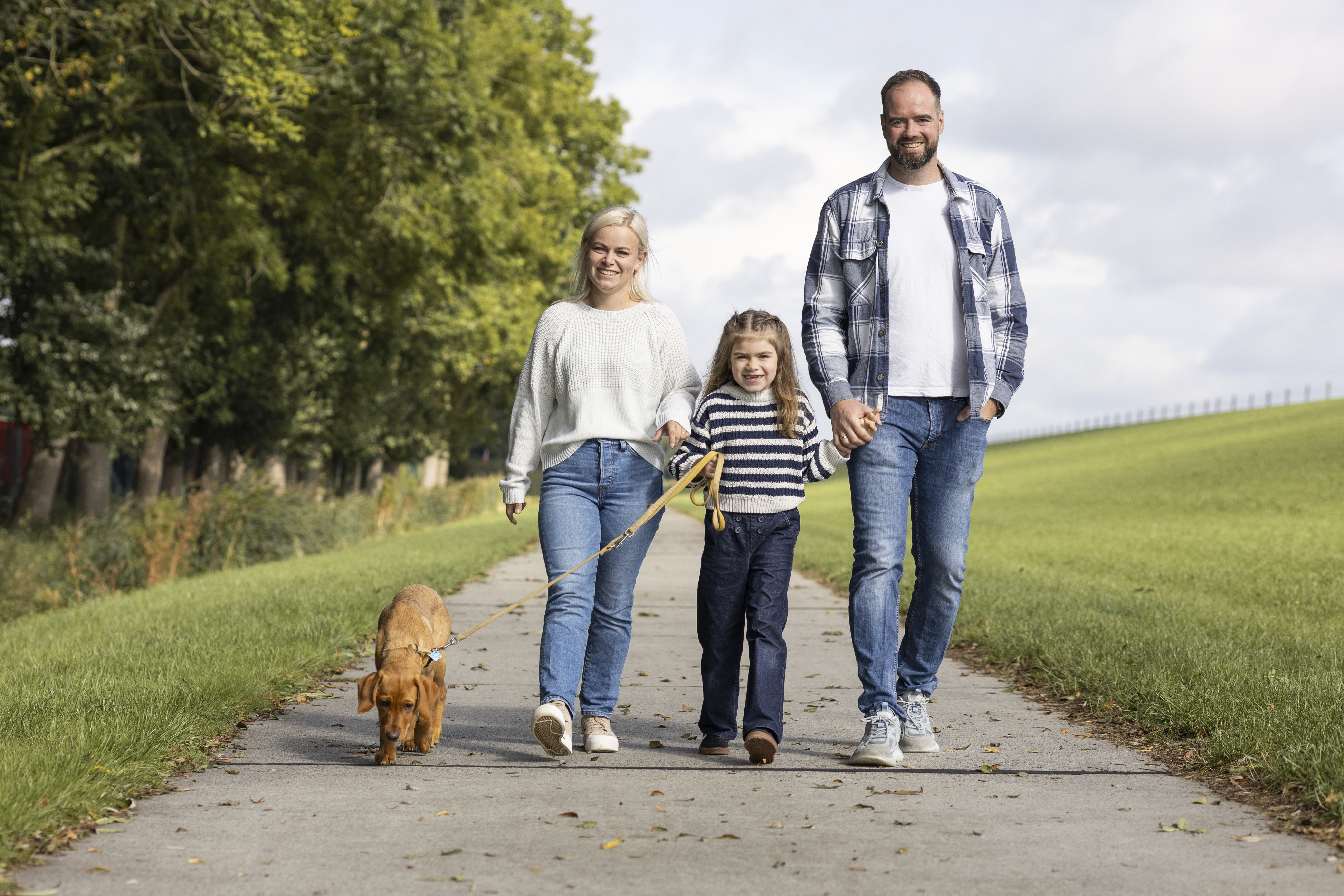 Mutter, Tochter und Vater wandern mit Hund über Weg durchs Grüne bei blauem Himmel bei Familienausflug in Cäciliengroden 