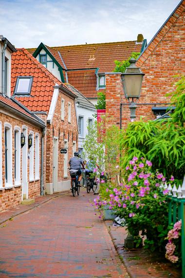 Radfahrer fahren durch eine schmale Straße in die Altstadt von Otterndorf
