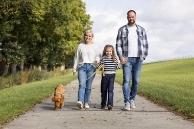 Mutter, Tochter und Vater wandern mit Hund über Weg durchs Grüne bei blauem Himmel bei Familienausflug in Cäciliengroden 