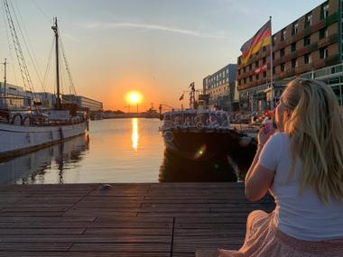 Frau pustet Seifenblasen am Hafenbecken bei Sonnenuntergang in Bremerhaven 