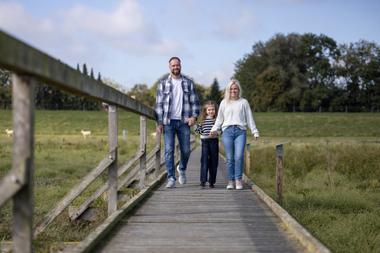 Vater, Tochter und Mutter wandern über Holzbohlenpfad vom Salzwiesenpfad Cäciliengroden bei Familienausflug