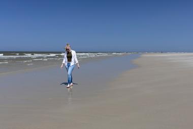 Frau spaziert am Strand von Spiekeroog