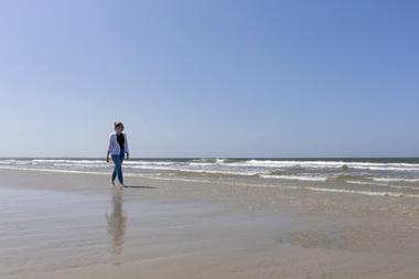 Frau beim Spaziergang entlang dem Strand von Spiekeroog