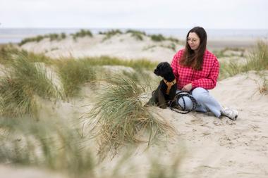 Frau mit Hund bei einem Spaziergang am Strand von Borkum