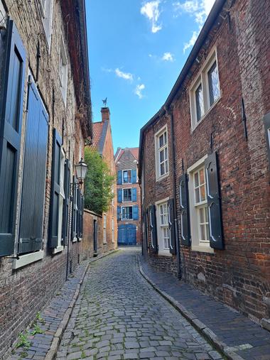 Blick durch eine schmale, historische Gasse in der Altstadt von Leer mit Kopfsteinpflaster und Häuserfassaden