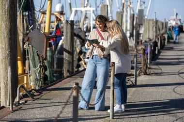 Zwei Frauen mit Nordsee-Reisepass am Kutterhafen in Neuharlingersiel